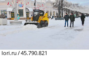 Трактор расчищает от снега оживленную пешеходную улицу в центре города, украшенную к предстоящему Новому году. Редакционное видео, видеограф Александр Бушков / Фотобанк Лори