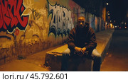 Young man sitting at night in urban street art scenery. Стоковое видео, видеограф Данил Руденко / Фотобанк Лори