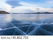 Baikal Lake in December. Unusual lenticular (Lat. Lenticularis) or lens-shaped clouds over blue clear ice with cracks of frozen Kurkut Bay and Small Sea. Beautiful winter landscape. Nature background. Стоковое фото, фотограф Виктория Катьянова / Фотобанк Лори