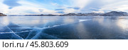 Baikal Lake in December. Panoramic view of blue clear ice with cracks of frozen Kurkut Bay of Small Sea Strait at sunset. Beautiful winter landscape. Nature background. Стоковое фото, фотограф Виктория Катьянова / Фотобанк Лори