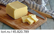 Fresh yellow butter sliced on wood cutting board. Cut butter block and pieces on a rustic table, blue linen napkin. Assortment of natural organic butter for breakfast. Baking ingredient. Close up view. Стоковое AI-видео, аниматор Марина Демидюк / Фотобанк Лори