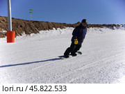 Зимние виды спорта и новогоднее настроение: на фотографии запечатлен юный сноубордист в динамичном движении, передающем энергию и радость зимнего отдыха. Редакционное фото, фотограф Ярославский Максим / Фотобанк Лори
