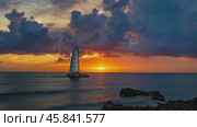 Catamaran sailing at sunset near a rocky coast. Стоковое AI-видео, аниматор Юрий Поздников / Фотобанк Лори