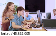 Friendly young students, girls and guys, actively involved in collaborative learning, sitting around table in computer lab excitedly discussing class project or engaging in group study session. Стоковое видео, видеограф Яков Филимонов / Фотобанк Лори
