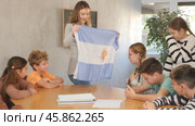 Group of curious preteen learners and young female teacher with flag of Argentina in classroom of academy. Стоковое видео, видеограф Яков Филимонов / Фотобанк Лори