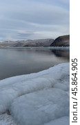 Vertical video of Baikal Lake during freeze-up. View of Olkhon Gate Strait and Olkhon Island in distance. Icy shore on frosty day. Scenic landscape. Natural background. Winter travels and outdoors. Стоковое видео, видеограф Виктория Катьянова / Фотобанк Лори