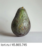 Rotten avocado fruit showing signs of spoilage on white background. Стоковое AI-изображение, AI-художник Иван Рябоконь / Фотобанк Лори