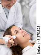 Professional mature female cosmetologist doing needleless high frequency mesotherapy in spa center. Non-invasive skin rejuvenation procedure. Стоковое фото, фотограф Яков Филимонов / Фотобанк Лори