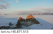 Shamanka Rock or Cape Burkhan at dawn in winter. Frozen Lake Baikal in the snow. Aerial view. Стоковое видео, видеограф Виктория Тельминова / Фотобанк Лори