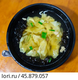 Wonton soup is cooked dumplings filled with meat or seafood. They are served in broth, usually enriched with onions and other ingredients. Chinese cuisine. Стоковое фото, фотограф Яков Филимонов / Фотобанк Лори