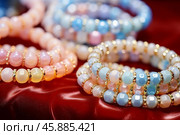 Colorful beaded bracelets resting on red silk, fashion accessories for women. Стоковое AI-изображение, AI-художник Иван Рябоконь / Фотобанк Лори