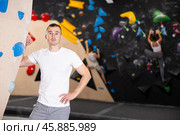Positive European man in sportswear is standing near climbing wall in gym. Стоковое фото, фотограф Яков Филимонов / Фотобанк Лори