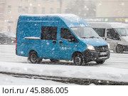 Blue cargo van drive during snowfall. Minibus moving on city road in blizzard at winter. Редакционное фото, фотограф Константин Григорьев / Фотобанк Лори