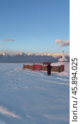 Vertical video of a girl tourist taking a photo of a white Buddhist stupa or suburgan against the backdrop of the snow-capped mountains of the Eastern Sayan Mountains at winter sunset. Стоковое видео, видеограф Виктория Катьянова / Фотобанк Лори