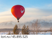 TUNKA VILLAGE, KYREN DISTRICT, BURYATIA, RUSSIA - January 04, 2025: People travel by hot air balloon over the snowy peaks of the Eastern Sayan Mountains during the winter holidays. Стоковое фото, фотограф Виктория Катьянова / Фотобанк Лори