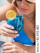 A young woman in a swimsuit and sunglasses in a Jacuzzi with a glass of Blue Lagoon cocktail on the background of the pool. The concept of a summer vacation, vacation and foam party. Стоковое фото, фотограф Photojuli / Фотобанк Лори