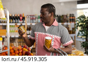 African man make choice choose consider canned pickled olives in store. Стоковое фото, фотограф Яков Филимонов / Фотобанк Лори