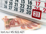 Лист календаря с чёрными и красными цифрами с красным бегунком на последнем дне месяца рядом купюры пять по пять тысяч рублей / A sheet of calendar with black and red numbers with a red runner on the last day of the month next to the banknotes of five thousand rubles each. Стоковое фото, фотограф Петроченко Мария Петровна / Фотобанк Лори