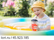 It's a hot summer day. Cute boy swims in the pool. The child drinks refreshing lemonade. The concept of summer holidays with children and refreshing drinks. Стоковое фото, фотограф Photojuli / Фотобанк Лори