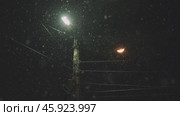 Snowfall on the background of a lantern in winter at night. Стоковое видео, видеограф Георгий Мякишев / Фотобанк Лори
