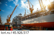 Shipbuilders working on large ship with cranes in dry dock at sunset. Стоковое AI-изображение, AI-художник Юрий Поздников / Фотобанк Лори