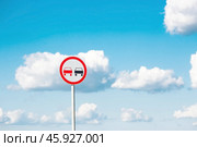 Traffic Laws. Attention. Overtaking is prohibited. A road sign on a metal pole against a background of blue sky and white clouds. Стоковое фото, фотограф Photojuli / Фотобанк Лори