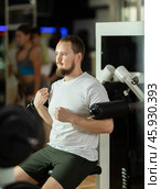 Bearded man in gym performs exercises for arm muscles using simulators and fitness center equipment. Стоковое фото, фотограф Яков Филимонов / Фотобанк Лори