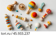 Assorted colorful wooden and felt baby rattles with unique designs on a white background. Natural sensory toys for infants and toddlers. Стоковое AI-изображение, AI-художник Екатерина Каболова / Фотобанк Лори
