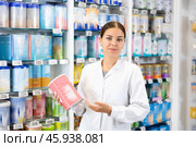 At pharmacy, apothecary holds jar of baby formula in hands and talks about properties of product. Стоковое фото, фотограф Яков Филимонов / Фотобанк Лори