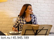 Beautiful woman in checkered shirt playing music synthesizer at home, composes music, learns musical scores. Стоковое фото, фотограф Ольга Яковенко / Фотобанк Лори