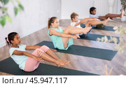 African girl perform boat asana - Paripurna navasana. Comprehensive hatha yoga class in mini group. Стоковое фото, фотограф Яков Филимонов / Фотобанк Лори
