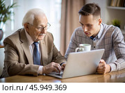 Pension. Saving money. Savings. The son teaches his retired father financial literacy. Стоковое AI-изображение, AI-художник Photojuli / Фотобанк Лори
