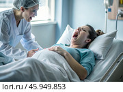 A pregnant woman in a hospital bed in the maternity ward. The woman is in labor and screaming in pain. Pregnancy and childbirth. Стоковое AI-изображение, AI-художник Photojuli / Фотобанк Лори