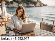 A young female freelance businessman is working on a laptop while on vacation by the sea or shopping in an online store. Стоковое AI-изображение, AI-художник Photojuli / Фотобанк Лори
