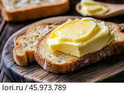 Slice of wholemeal bread with butter curl. Buttering toast. Yellow butter scattered on a piece of bread. Bread with toasting and spreading butter. Generous spread of butter on a rustic bread slice. Стоковое AI-изображение, AI-художник Марина Демидюк / Фотобанк Лори