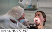 Mature man doctor dentist in white coat examines oral cavity of girl patient in dentistry. Стоковое видео, видеограф Яков Филимонов / Фотобанк Лори