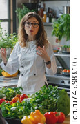 Female chef explaining recipe with vegetables in kitchen. Стоковое AI-видео, аниматор Юрий Поздников / Фотобанк Лори