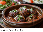Delicious meatballs with yogurt sauce garnished with parsley in traditional tagine. Стоковое AI-изображение, AI-художник Иван Рябоконь / Фотобанк Лори
