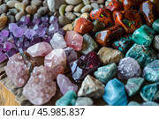 Colorful tumbled gemstones creating a vibrant display on a wooden surface. Стоковое AI-изображение, AI-художник Иван Рябоконь / Фотобанк Лори