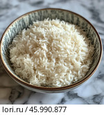 A bowl of white boiled rice that looks fluffy and airy. The rice is piled up, the grains are long-grained and well separated. The bowl has a ceramic texture with subtle patterns along the edges and is placed on a marble surface. The photo is taken in a minimalist style, emphasizing the simplicity and naturalness of the dish. Стоковое AI-изображение, AI-художник Анна Кривицкая / Фотобанк Лори
