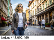 Disability. Loss of vision. A blind woman with a cane and sunglasses is walking down a city street. International Day of the Blind on November 13. Стоковое AI-изображение, AI-художник Photojuli / Фотобанк Лори