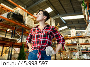 Thoughtful female storekeeper looking for tedious goods in building materials warehouse indoor. Стоковое фото, фотограф Яков Филимонов / Фотобанк Лори