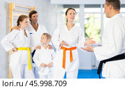 After completing family session and karate training, parents talk with male coach. Стоковое фото, фотограф Яков Филимонов / Фотобанк Лори