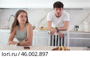 Upset young woman sitting at the kitchen-table with her back to her husband disputing with her. Стоковое видео, видеограф Яков Филимонов / Фотобанк Лори
