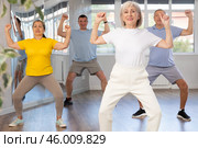 Elderly woman practicing Tai Chi with group in training room. Стоковое фото, фотограф Яков Филимонов / Фотобанк Лори