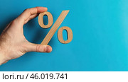 Wood percentage sign in a human hand. Blue studio background, copy space. Symbol percent. Seasonal sale, discount. Rate for finance, return. Investment ROI, credit, mortgage, tax, marketing, promotion. Стоковое AI-видео, аниматор Марина Демидюк / Фотобанк Лори