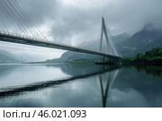 Modern cable stayed bridge spanning serene waterway in misty mountain landscape. Стоковое AI-изображение, AI-художник Иван Рябоконь / Фотобанк Лори