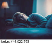 Задумчивая девушка лежит в комнате на диване в шерстяном свитере под мягким желтым светом торшера. Стоковое AI-изображение, AI-художник Сергей Никифоров-Гордеев / Фотобанк Лори