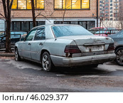 Старый брошенный автомобиль Mercedes W124 стоит во дворе дома. Неисправный сломанный автохлам. Редакционное фото, фотограф Константин Григорьев / Фотобанк Лори