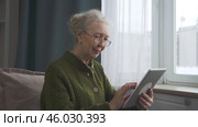 Elderly woman reading an online article on a tablet. Стоковое видео, видеограф Владимир Федоров / Фотобанк Лори